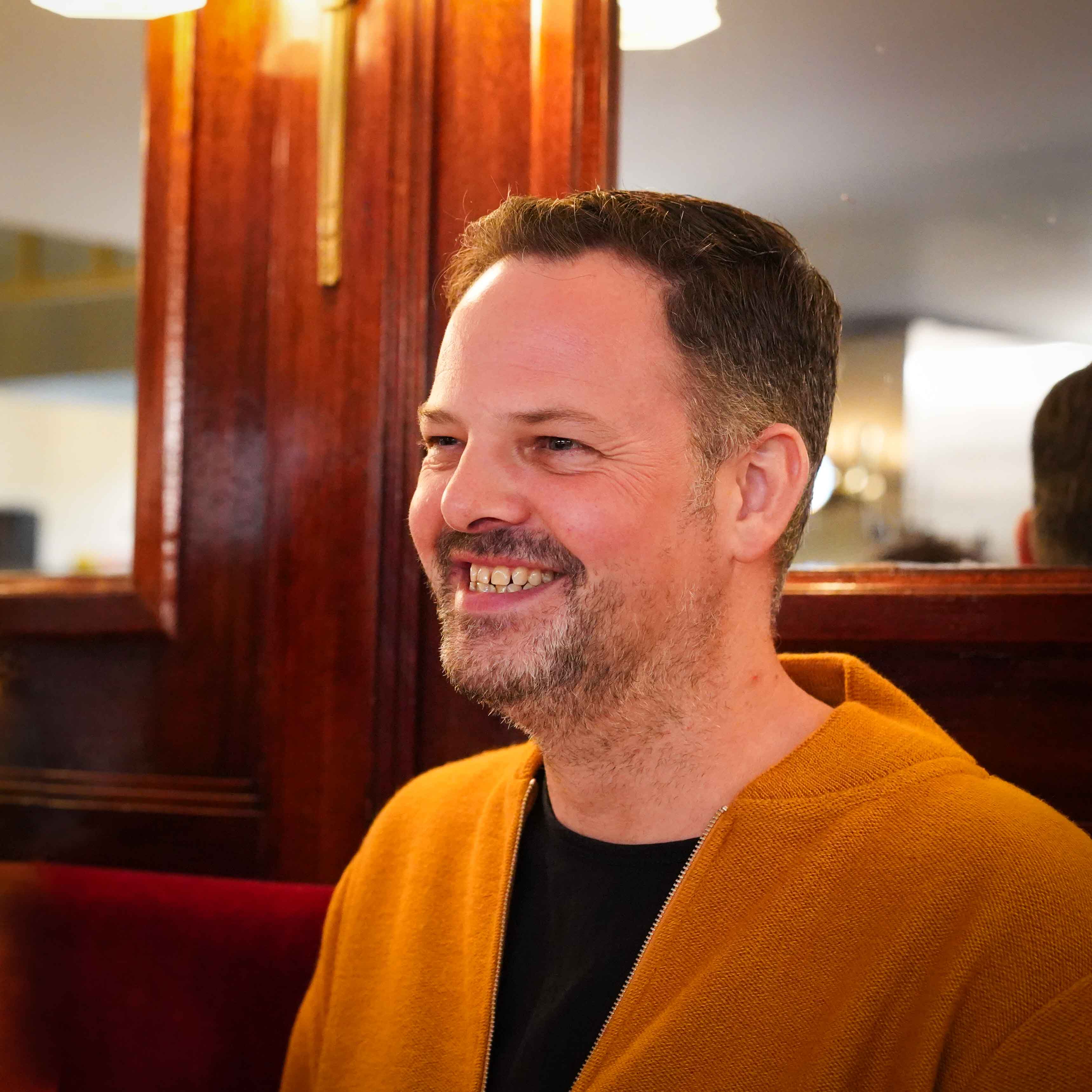 White man sitting at restaurant smiling