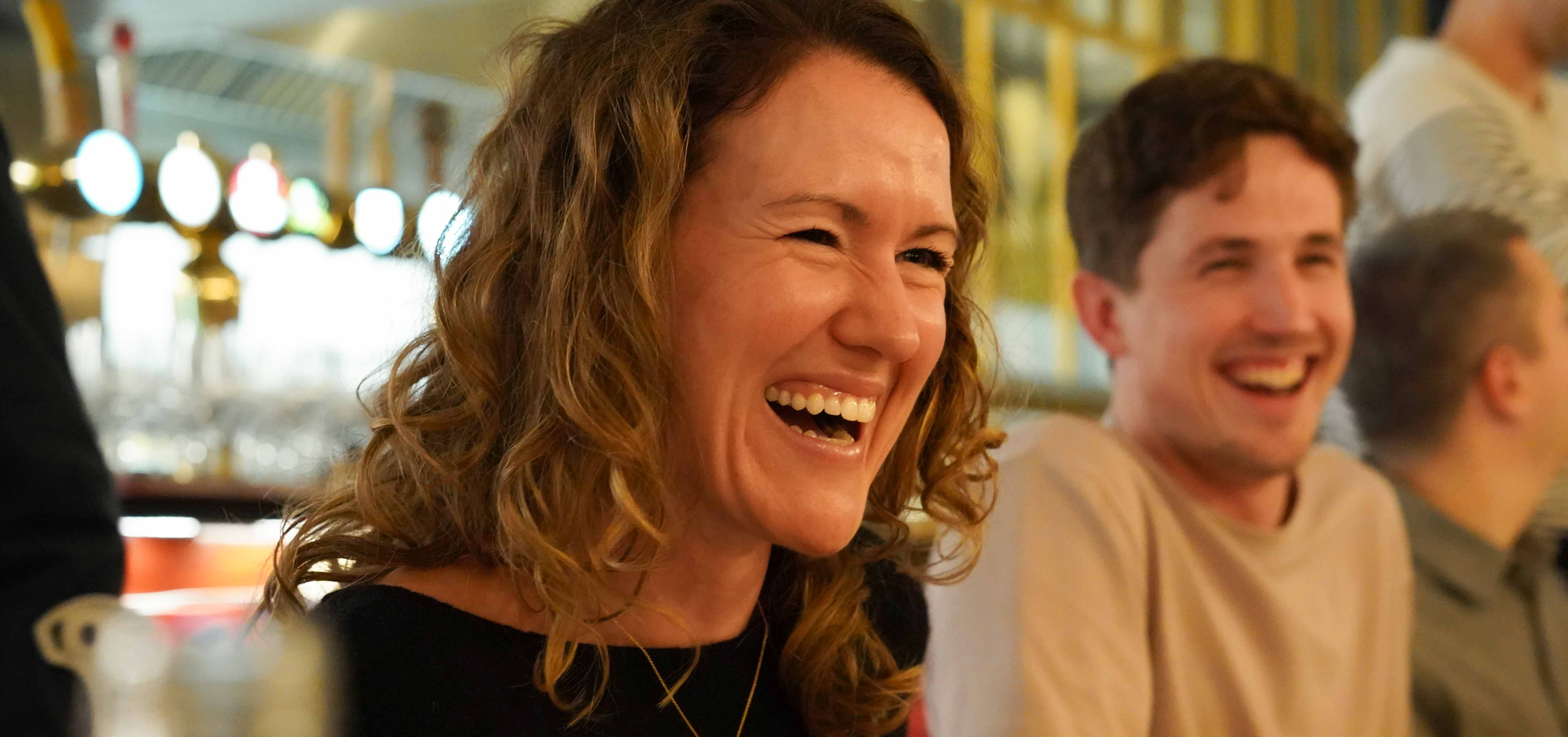 White woman and man laughing while sitting at restaurant